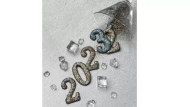 En bild där årtalen 2022 och 2023 runnit ur ett tippat glas, tvåan och trean på slutet ligger över varandra för att symbolisera övergången till ett nytt år.