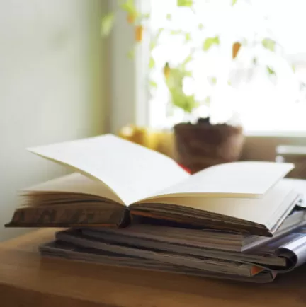 En öppen bok på en trave böcker