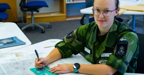 kvinna i uniform vid ett skrivbord med penna i handen