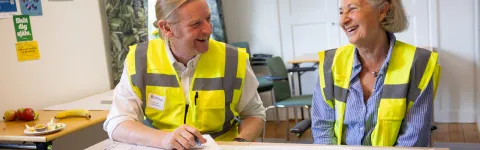 en man och en kvinna i varselvästar skrattar