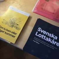 Bilden visar ett bord med två olika flyers. En med info om Lottakåren och "Om krisen eller kriget kommer"