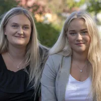 Två kvinnor tittar rakt in i kameran och ler lätt.