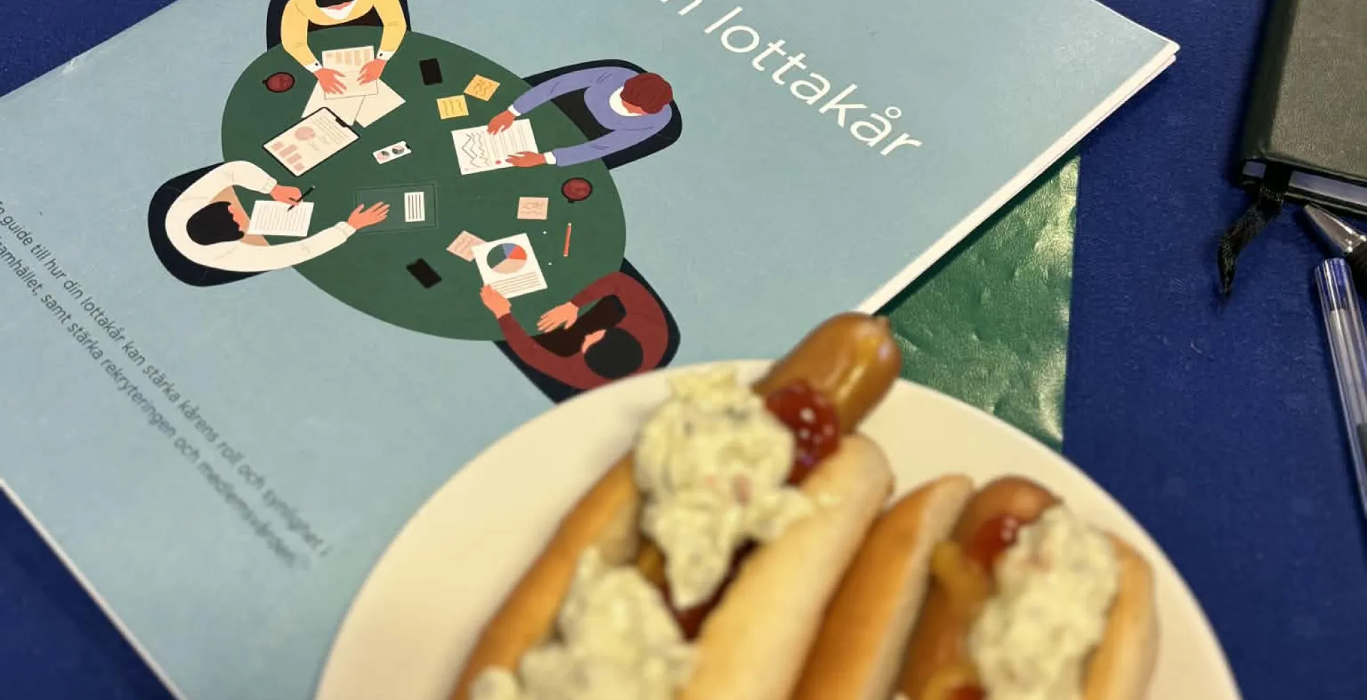 Bilden visar två korv med bröd samt dokumentationsunderlag för arbetet med Stärk din lottakår.