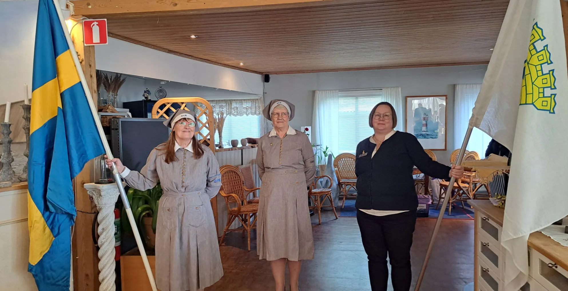 Lottor står med fana vid jubileumsfirandet